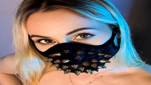 Angry Rose en tenue noire avec harnais et posture dominante dans une ambiance sombre