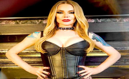 Lady Phoenix en body noir avec une posture dominante devant une cheminée