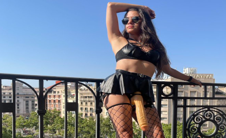 Mistress Erinia en extérieur avec une tenue noire et une présence visuelle marquée