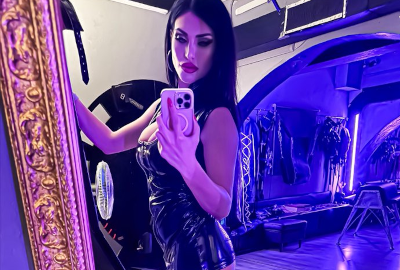 Mistress Iside en tenue noire dans un studio avec une ambiance immersive et stylisée