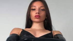 Mistress Lolita Hush en tenue noire avec une présence dominante dans un intérieur moderne