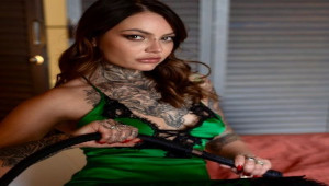 Nikky French en tenue élégante avec une posture confiante assise dans un fauteuil noir